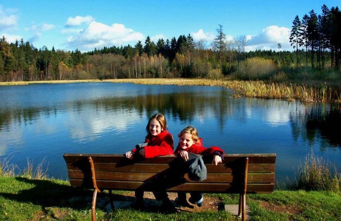 Kinder sitzend auf Bank am See